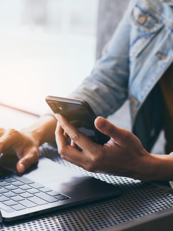 A black woman sitting at a table with a laptop and a cell phone