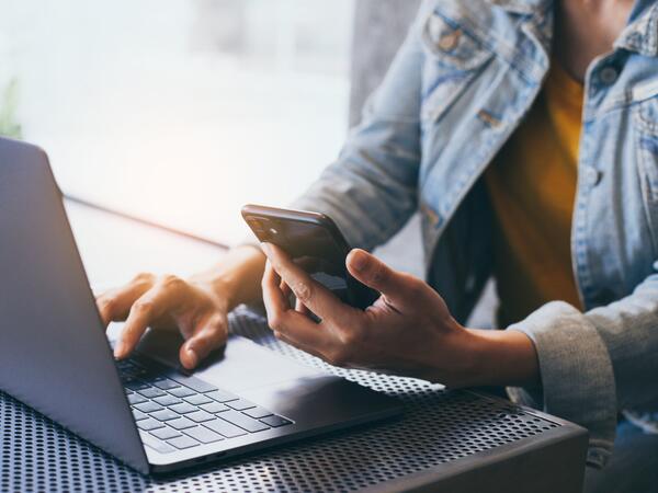 A black woman sitting at a table with a laptop and a cell phone