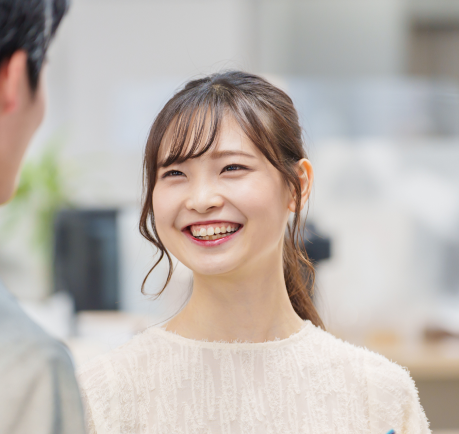A young Asian woman smiling and having a conversation with another man 