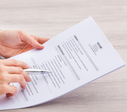 A person holding on a printed out resume and a pen 