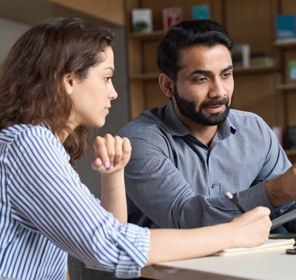 An Asian man and an Asian woman taking down notes in a serious manner