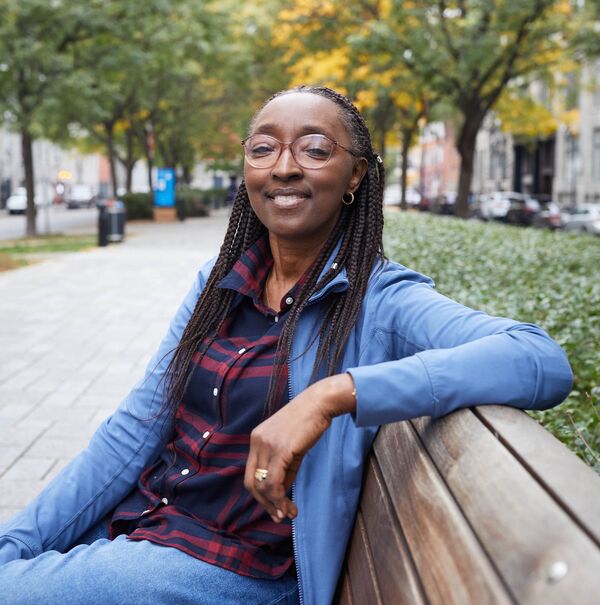 Black woman sitting on a sidewalk bench