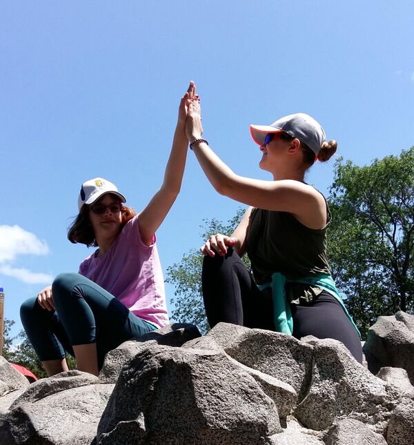 Two women on a hike high fiving 