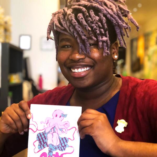 A joyful black woman holding a paper with an illustration of an octopus