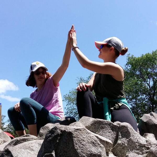 Two women on a hike high fiving 